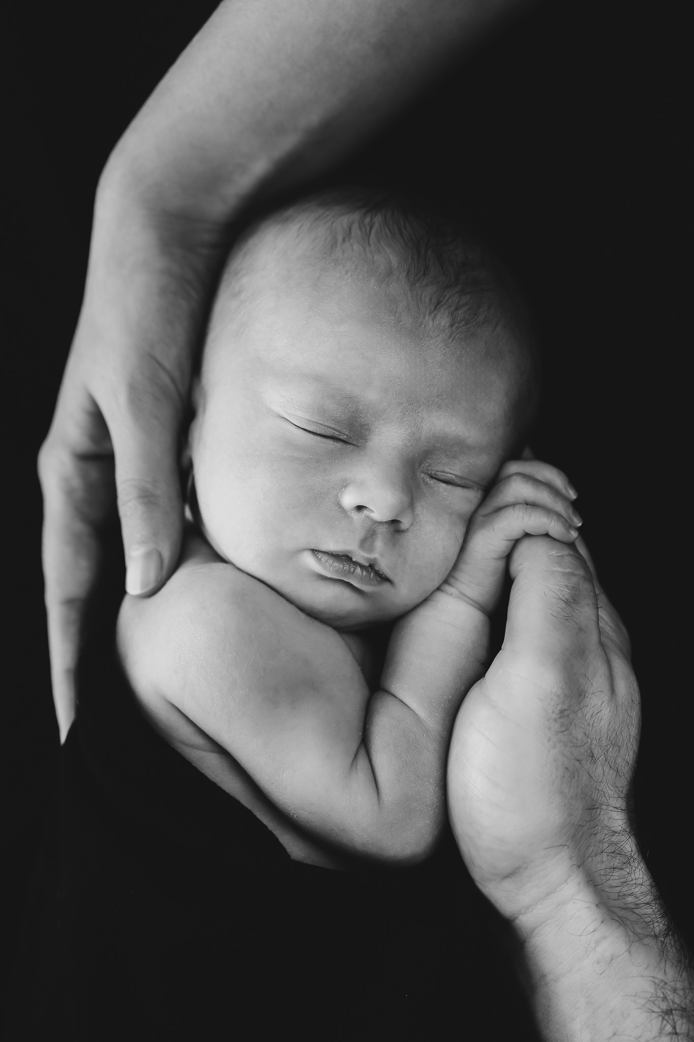 Pasgeboren baby tussen de handen van papa en mama